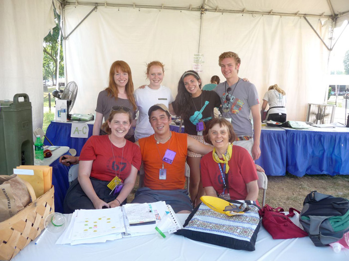Betty Belanus and her interns convene at the Volunteer Tent for an afternoon meeting. Standing, left to right: Interns Hester Clarke, Casey Carlson and Lauren Lauzon, and Accessibility Aide Brendon Ziebarth; seated, left to right: Interns Meghan Burke and Jeremy Krones, and Curator Betty Belanus