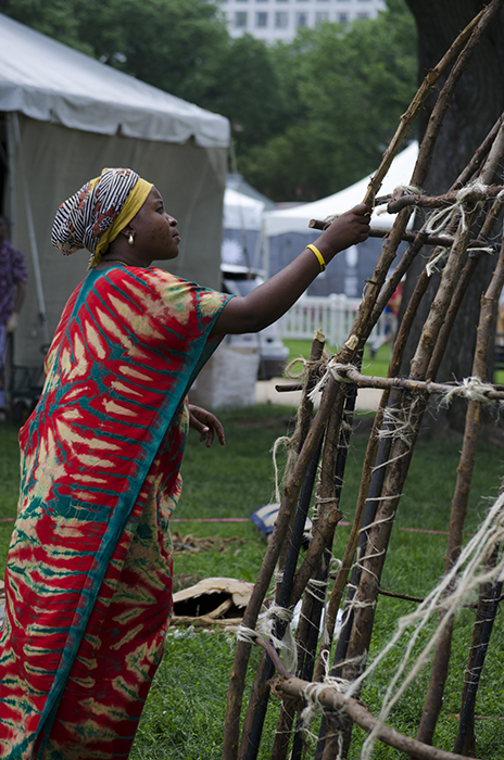 A Pokomo woman works on the frame of a domed hut, built with branches shipped from Kenya.