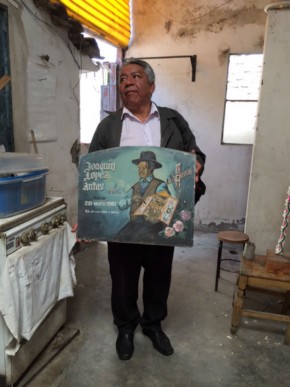 Alfredo Lopez Morales holds a retablo advertisement for Joaquin Lopez Antas, his grandfather. Photo by Jackie Flanagan Pangelinan, Ralph Rinzler Folklife Archives